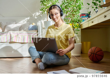 Teenage girl with headphones studying at home using a laptop 97855646