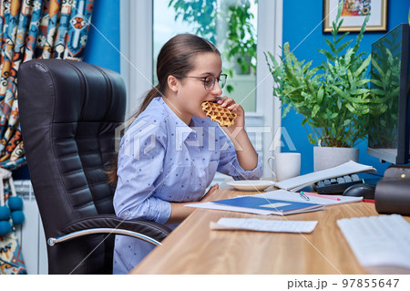 Teenage girl at home at computer is studying having a snack with tea Teenage girl at home at computer is studying having a snack with tea 97855647