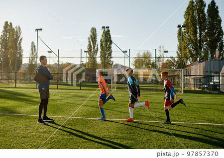 Kids practicing soccer on grass field under football coach control 97857370
