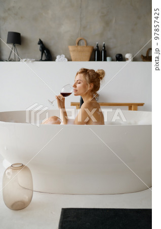 Sensual relaxed woman drinking red wine while taking bath with foam Sensual relaxed woman drinking red wine while taking bath with foam 97857425