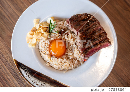 Beef with beef fat fried rice, a dish consisting of a bowl of rice topped with rare beef served with egg yolk Beef with beef fat fried rice, a dish consisting of a bowl of rice topped with rare beef served with egg yolk 97858064