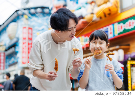 大阪観光をしながら食べ歩きをする親子 97858334