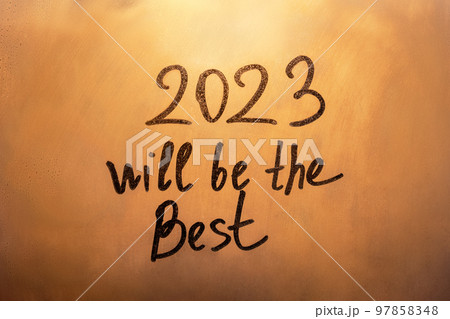 Numbers 2023 and lettering will be the Best of new year paint with finger on splashed by rain foggy glass on orange sunset window Numbers 2023 and lettering will be the Best of new year paint with finger on splashed by rain foggy glass on orange sunset window 97858348