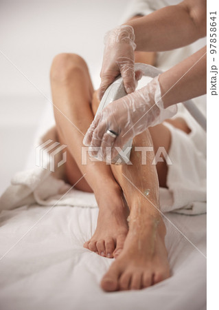 leg at spa, Hair removal, ipl cosmetology. Low section of young woman receiving laser treatment on leg at spa for laser epilation, cosmetology and cosmetology, epilation 97858641