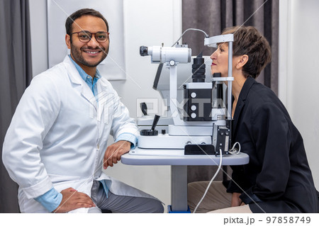 Male doctor working on optometric equipment at clinic 97858749