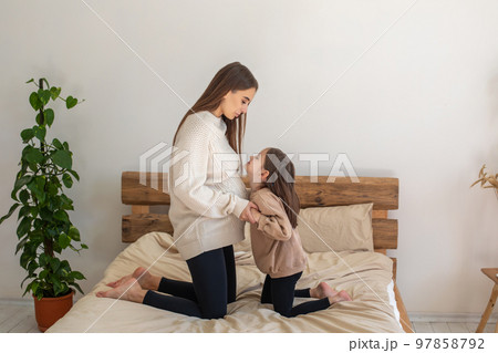 Little girl looking interested while listening to babys moves in her moms belly Little girl looking interested while listening to babys moves in her moms belly 97858792