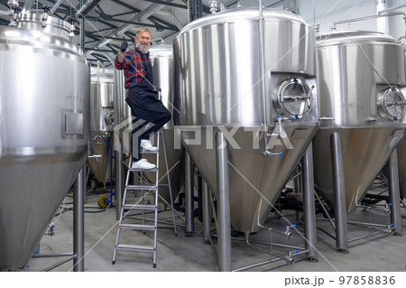 Factory worker checking the tanks with beer and looking satisfied with the result 97858836