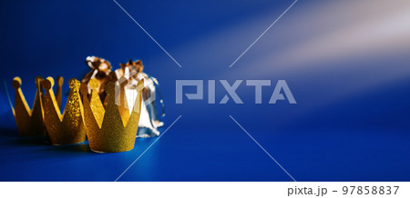 Happy Epiphany Day, Three Kings Day greeting card with three gold crowns and gifts on blue background. Concept for Dia de Reyes Magos day, three Wise Men, Epiphany Christian feast day 97858837