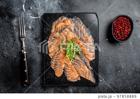 Salmon carpaccio with microgreens on marble board. Black background. Top view Salmon carpaccio with microgreens on marble board. Black background. Top view 97858889