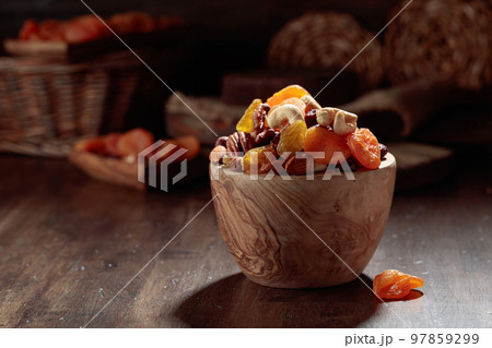 Dried fruits and assorted nuts on a wooden table. 97859299