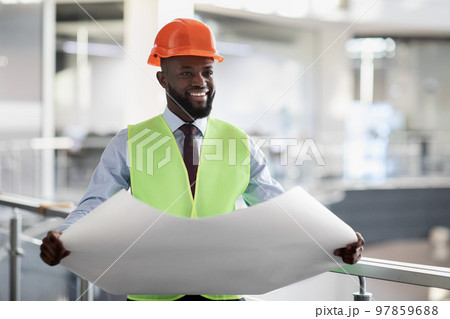 Cheerful black civil engineer in safety workwear holding draft Cheerful black civil engineer in safety workwear holding draft 97859688