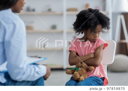 Angry girl with arms crossed on chest talking to psychologist Angry girl with arms crossed on chest talking to psychologist 97859870
