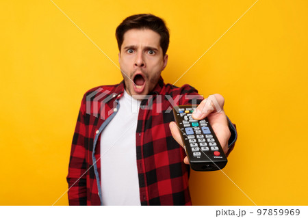 Scared young guy watching tv holding remote control 97859969