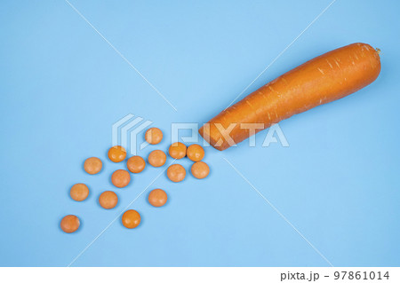 Orange vitamin D pills and a carrot 97861014