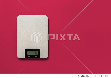 Digital kitchen scales against viva magenta background. 97861238