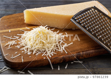 Finely grated parmesan over wooden cutting board. 97861239