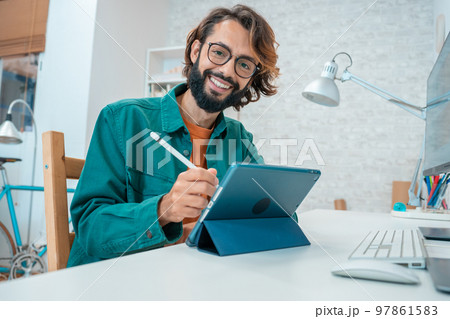 Young designer looking at camera while working with graphics tablet Young designer looking at camera while working with graphics tablet 97861583