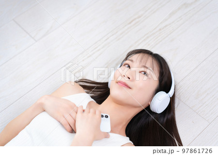 フローリングに寝転んでスマホ音楽に浸る女性 フローリングに寝転んでスマホ音楽に浸る女性 97861726