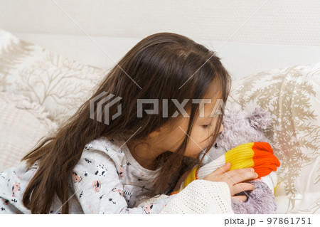 Little girl measure temperature by kissing forehead of sick teddy bear. Doctor, play with stuffed toy, treatment. Little girl measure temperature by kissing forehead of sick teddy bear. Doctor, play with stuffed toy, treatment. 97861751