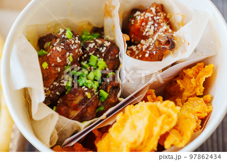 caramelized chicken with sesame and garlic, meat strips in paper bucket  97862434