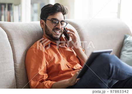 Young middle eastern businessman working from home, using gadgets 97863342
