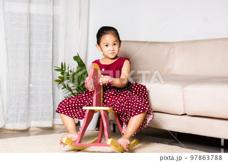 Asian cute little girl swinging riding toy horse, Smiling kid playing horse rocking chair at home in living room, Happy time to play during self kindergarten preschool Asian cute little girl swinging riding toy horse, Smiling kid playing horse rocking chair at home in living room, Happy time to play during self kindergarten preschool 97863788