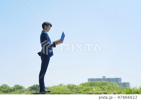 屋外でパソコンを使うビジネスマン 97866622