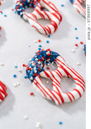 Dipping pretzels twists into melted chocolate to make red, white, and blue chocolate-covered pretzel twists. Dipping pretzels twists into melted chocolate to make red, white, and blue chocolate-covered pretzel twists. 97868997