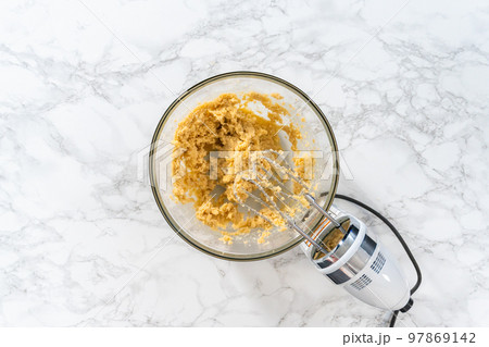 Flat lay. Mixing ingredients in a large glass mixing bowl to bake peppermint white chocolate cookies. 97869142