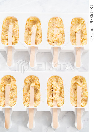 Filling silicone molds with cake crumbs to prepare mermaid cakesicles. 97869239