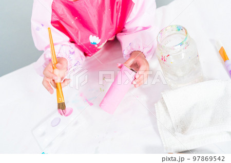 Little girl making a unicorn out of the toilet paper roll and craft paper. 97869542