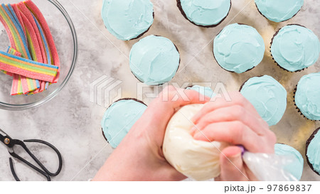 Flat lay. Step by step. Decorating chocolate cupcakes with buttercream frosting and rainbow candy. 97869837