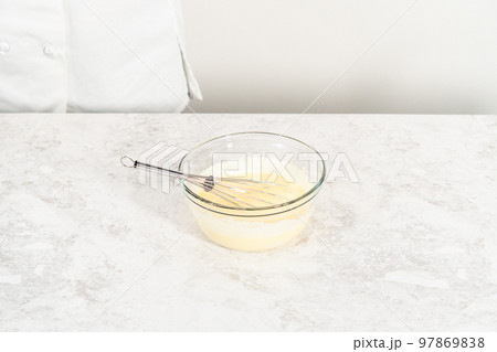 Mixing ingredients in a glass mixing bowl to bake funfettti bundt cake. Mixing ingredients in a glass mixing bowl to bake funfettti bundt cake. 97869838