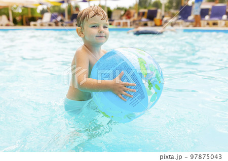 Kid swim, dive, leisure and playing inflatable ball in pool at vacation 97875043