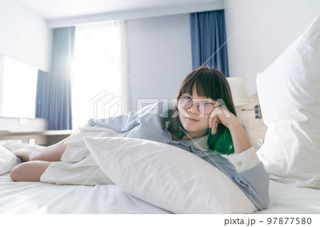 Asian young glasses woman lie on her side on the bed in the morning. 97877580