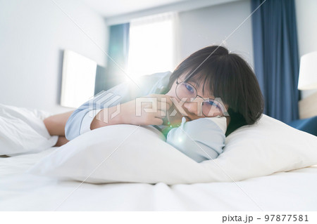 Asian young glasses woman lie on her side on the bed in the morning. 97877581