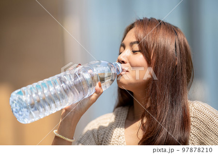 Asian Woman drinks big bottle water in outdoor green bokeh tree background. Asian Woman drinks big bottle water in outdoor green bokeh tree background. 97878210
