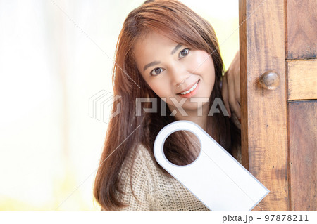 Asian Cute woman hold door tag and smile in front of wood door at outdoor field. Asian Cute woman hold door tag and smile in front of wood door at outdoor field. 97878211