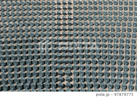 Gray folding seats in the stands of a large outdoor stadium, top view. Seats for fans of their favorite teams. Empty plastic chairs for sports arenas and halls with floor mounting. Gray folding seats in the stands of a large outdoor stadium, top view. Seats for fans of their favorite teams. Empty plastic chairs for sports arenas and halls with floor mounting. 97879775