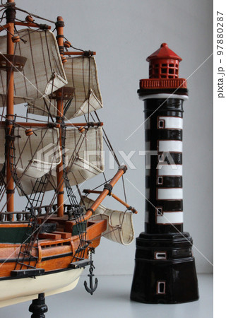 Toy Frigate With Fabric Sails Turned Bow To A Miniature Lighthouse Stock Photo Toy Frigate With Fabric Sails Turned Bow To A Miniature Lighthouse Stock Photo 97880287