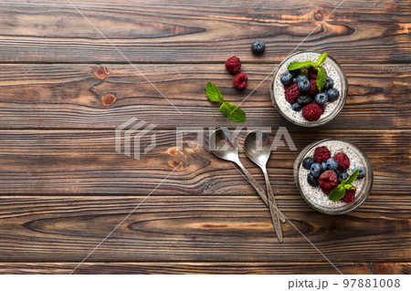 Healthy breakfast or morning with chia seeds vanilla pudding raspberry and blueberry berries on table background, vegetarian food, diet and health concept. Chia pudding with raspberry and blueberry 97881008