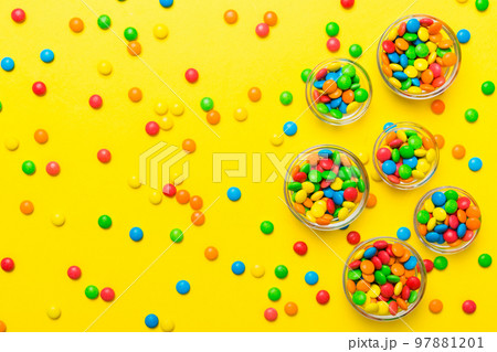 different colored round candy in bowl and jars. Top view of large variety sweets and candies with copy space different colored round candy in bowl and jars. Top view of large variety sweets and candies with copy space 97881201