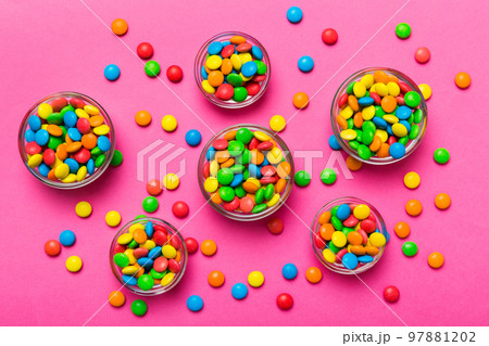 different colored round candy in bowl and jars. Top view of large variety sweets and candies with copy space different colored round candy in bowl and jars. Top view of large variety sweets and candies with copy space 97881202