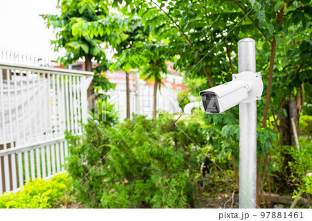 CCTV camera is installed in the garden with blur green tree background for monitor and safety system control around that area. 97881461