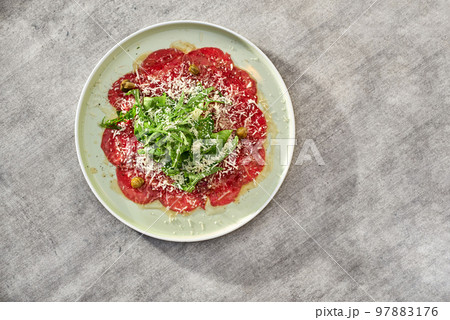 Marbled beef carpaccio with arugula, capers and parmesan cheese Marbled beef carpaccio with arugula, capers and parmesan cheese 97883176