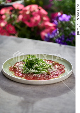 Marbled beef carpaccio with arugula, capers and parmesan cheese Marbled beef carpaccio with arugula, capers and parmesan cheese 97883178