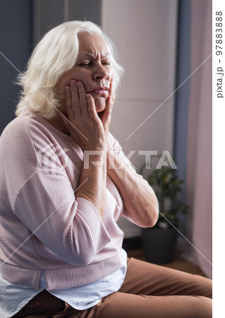 Woman touching mouth with hand with painful expression because of toothache  97883888