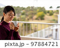 テラスでコーヒーを飲んでゆっくりする女性 テラスでコーヒーを飲んでゆっくりする女性 97884721