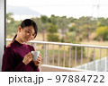 テラスでコーヒーを飲んでゆっくりする女性 テラスでコーヒーを飲んでゆっくりする女性 97884722