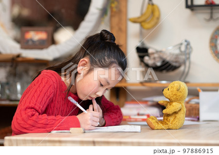 自宅で勉強をする少女と見守るテディーベア 自宅で勉強をする少女と見守るテディーベア 97886915